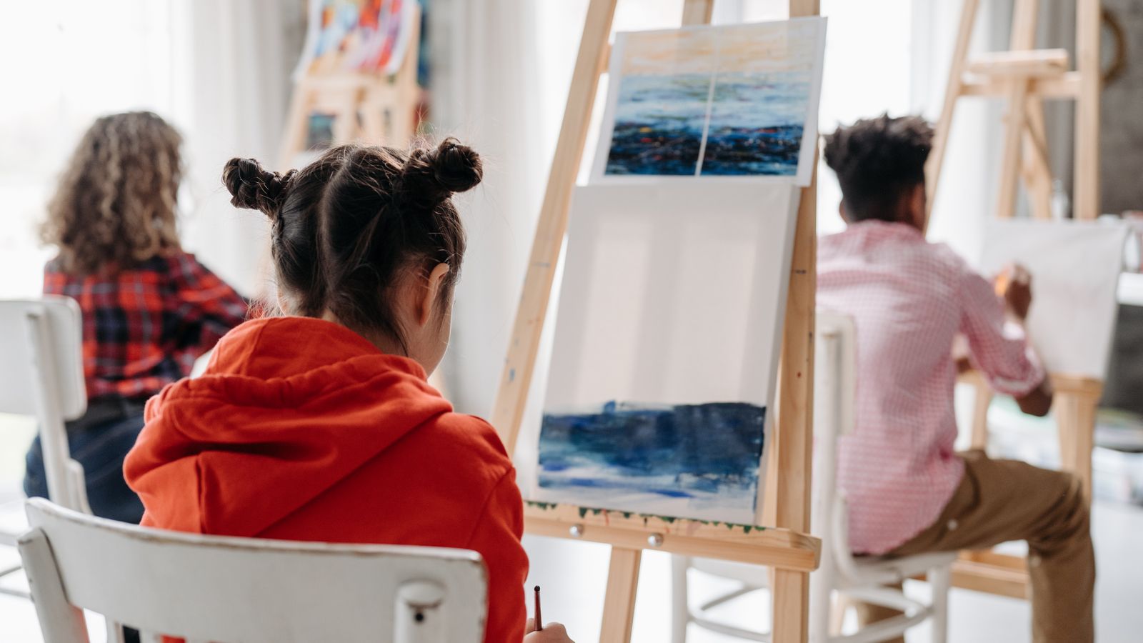 Children painting on easels during a creative art class