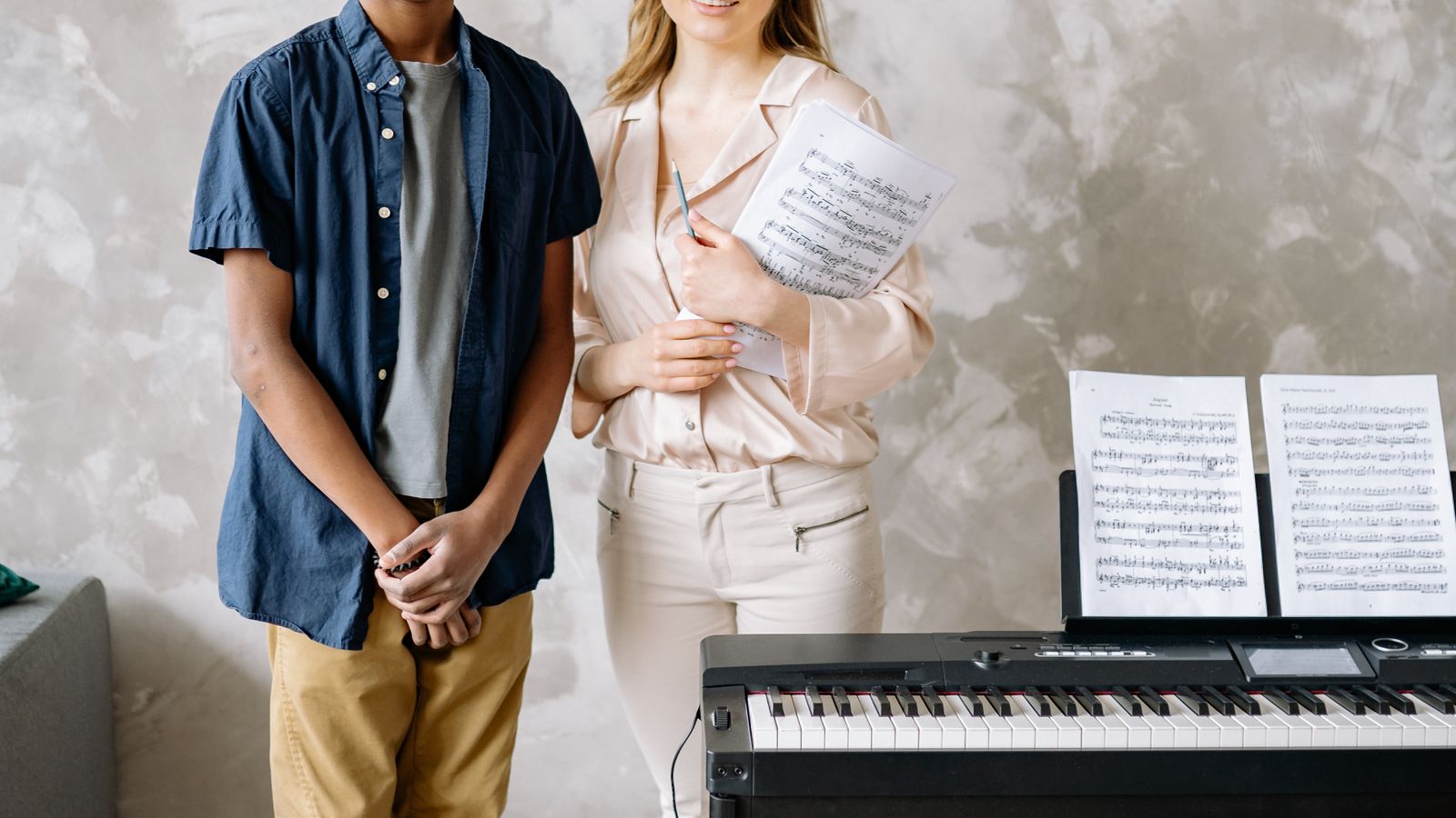A music teacher and student practising piano together