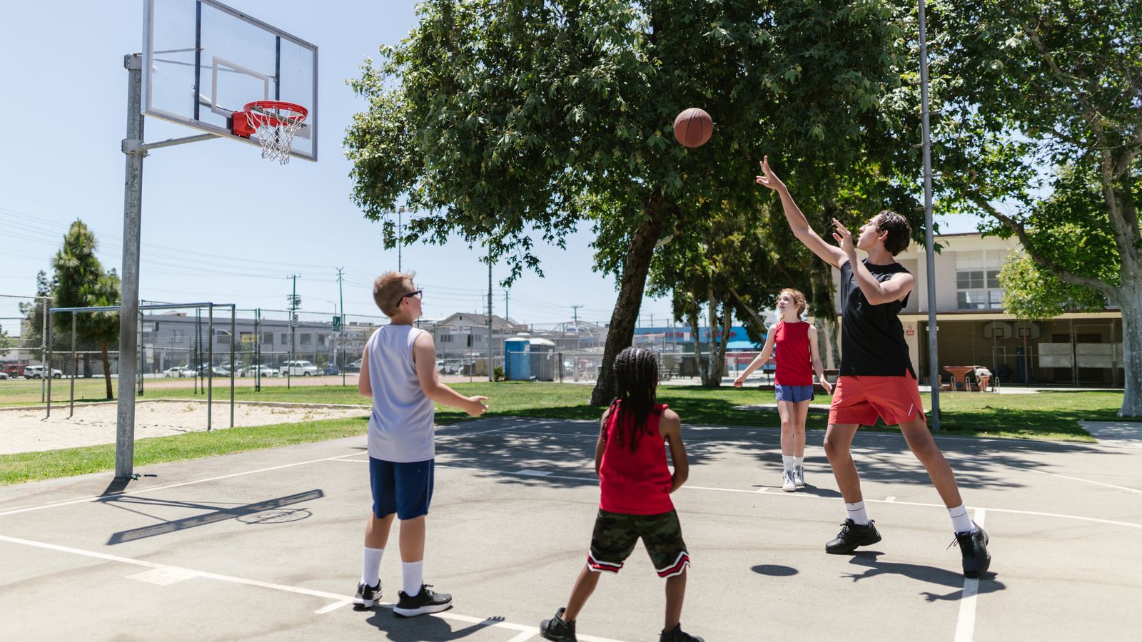 Children playing basketball together on an outdoor court